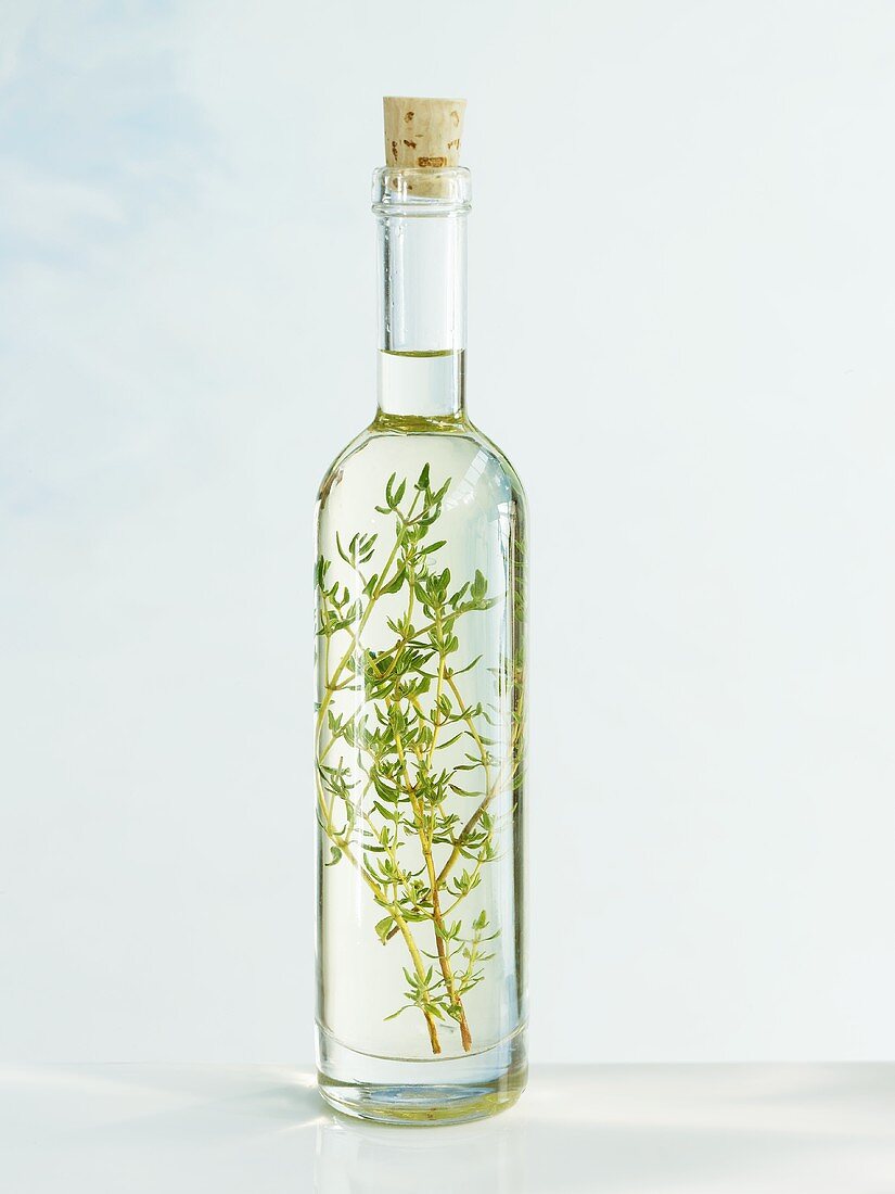 Eine Flasche Sonnenblumenöl mit Thymian