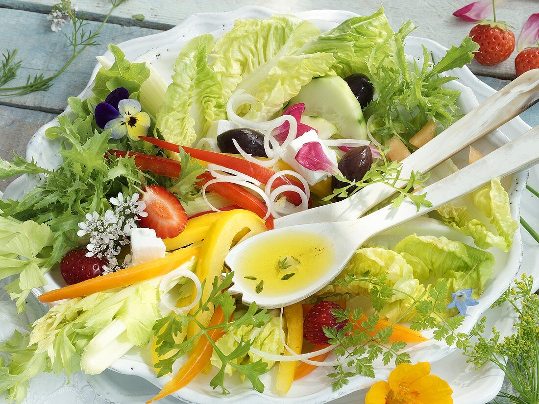 A mixed summer salad with edible flowers and strawberries