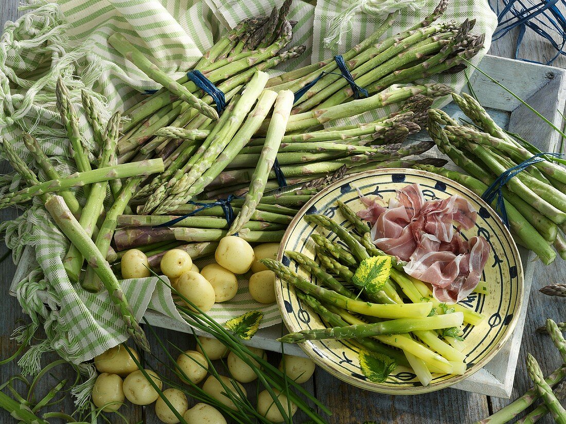 An arrangement of green asparagus, ham and potatoes