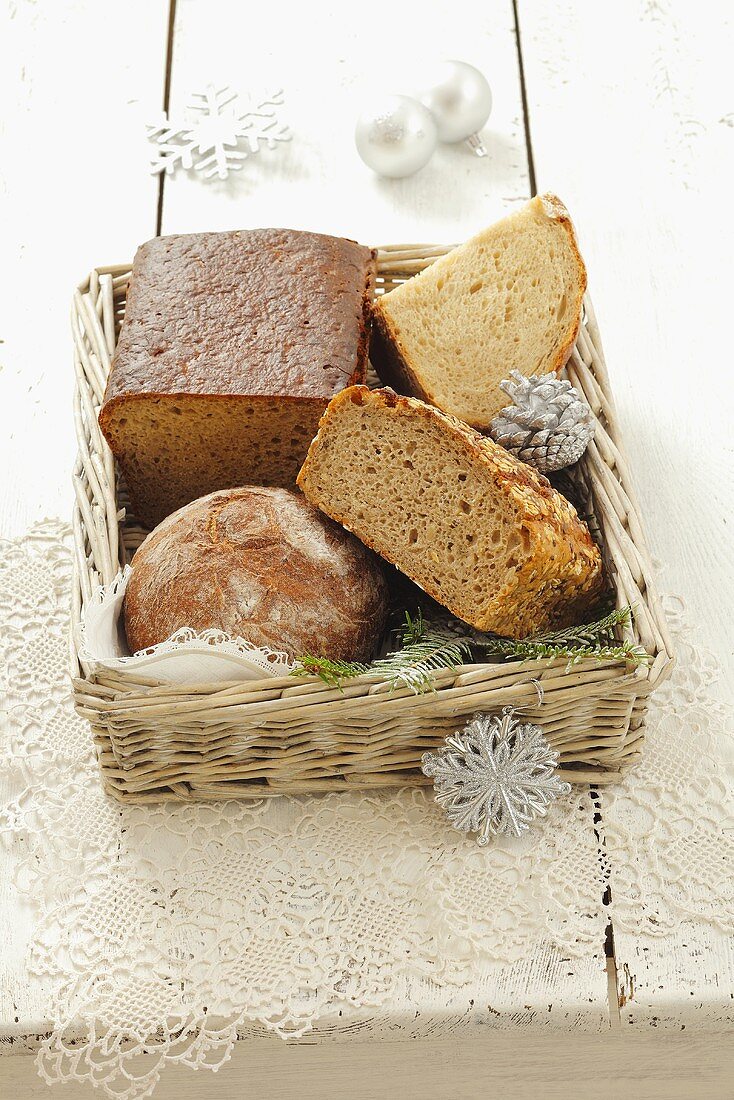 Various types of bread in a bread basket with Christmas decorations