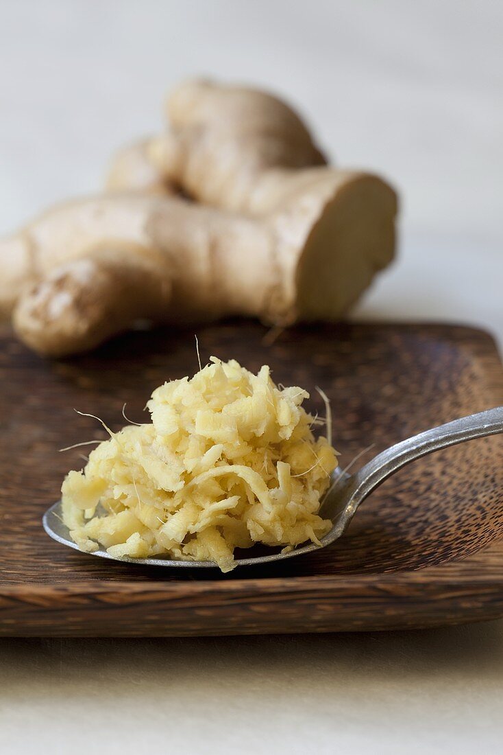 Ingwerwurzel und Löffel mit geraspeltem Ingwer