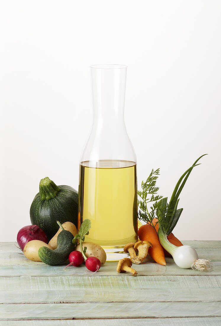 Oil in a carafe with various types of vegetables