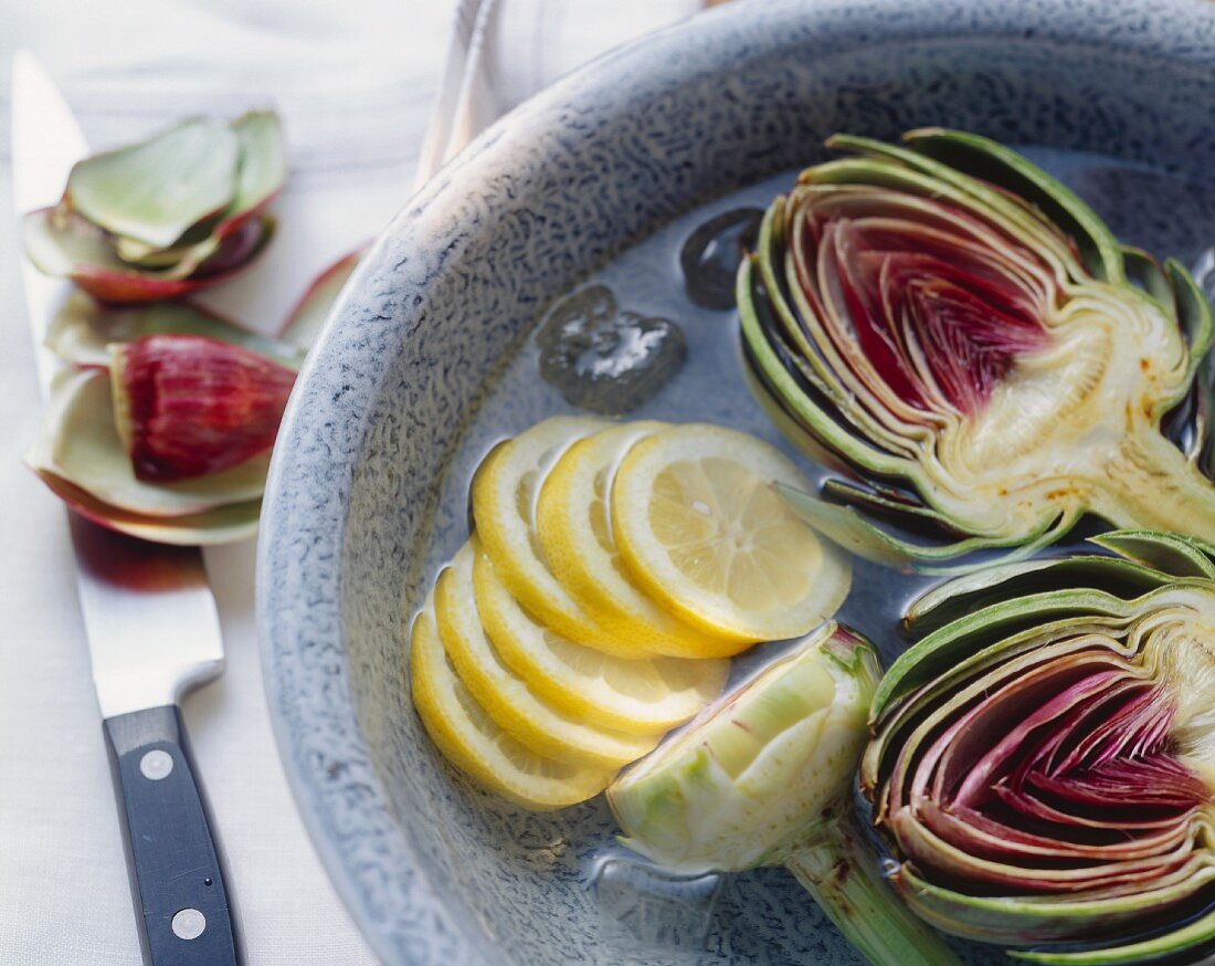 Artichokes and lemon slices in iced water