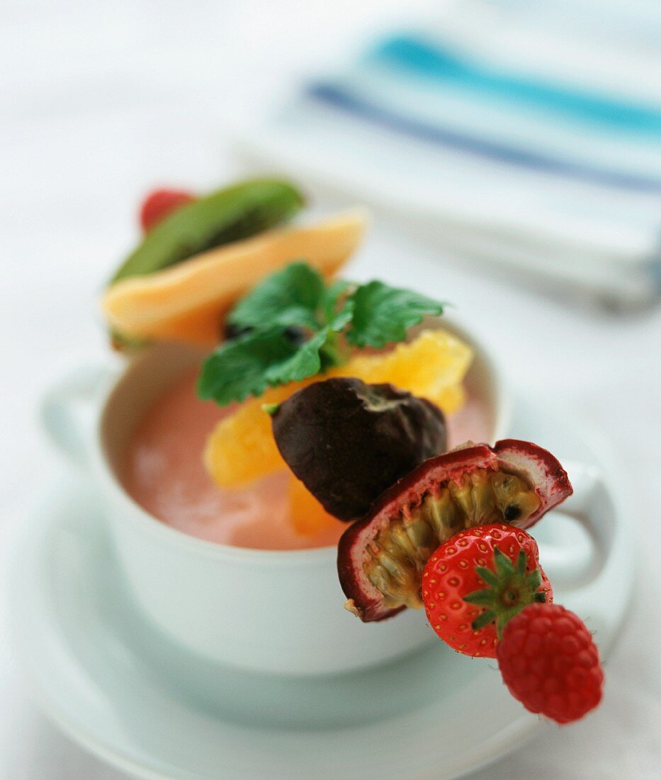 A fruit kebab resting on a soup bowl filled with strawberry quark