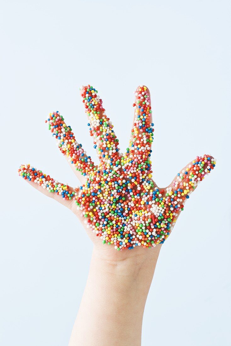 Child's hand covered in sprinkles