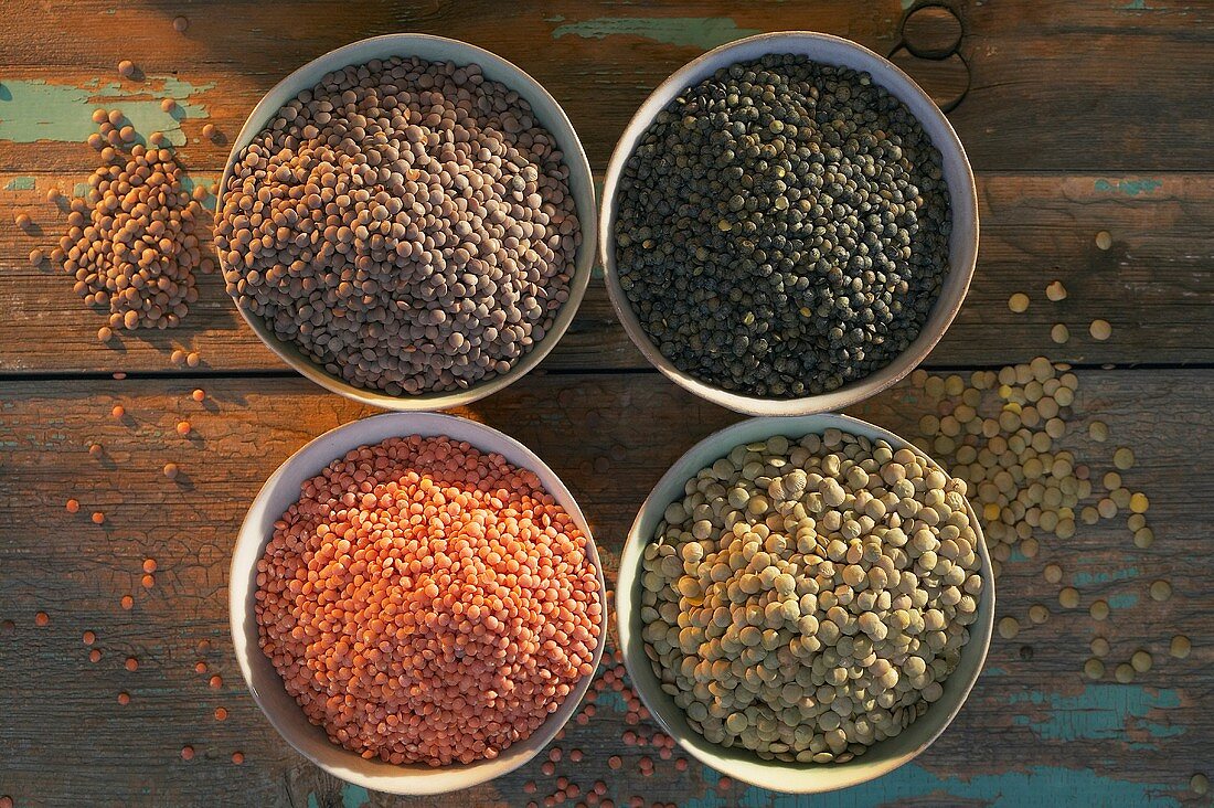 Various types of lentils in bowls (overhead view)