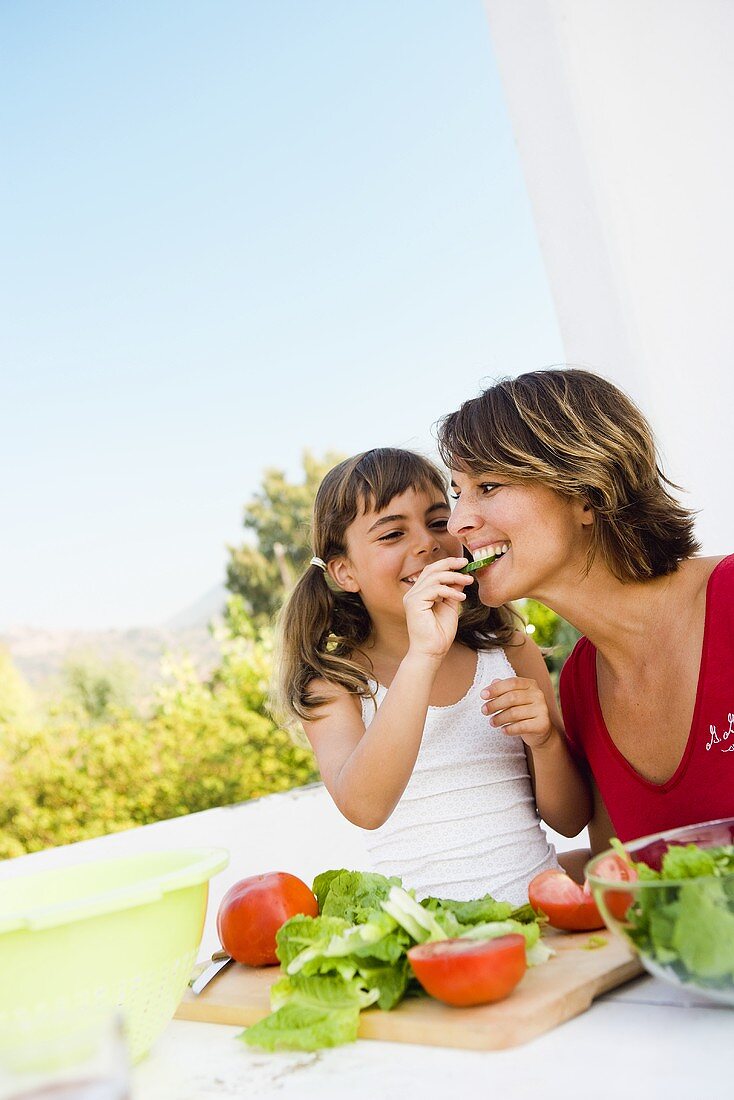 Mother and daughter preparing salad out of doors