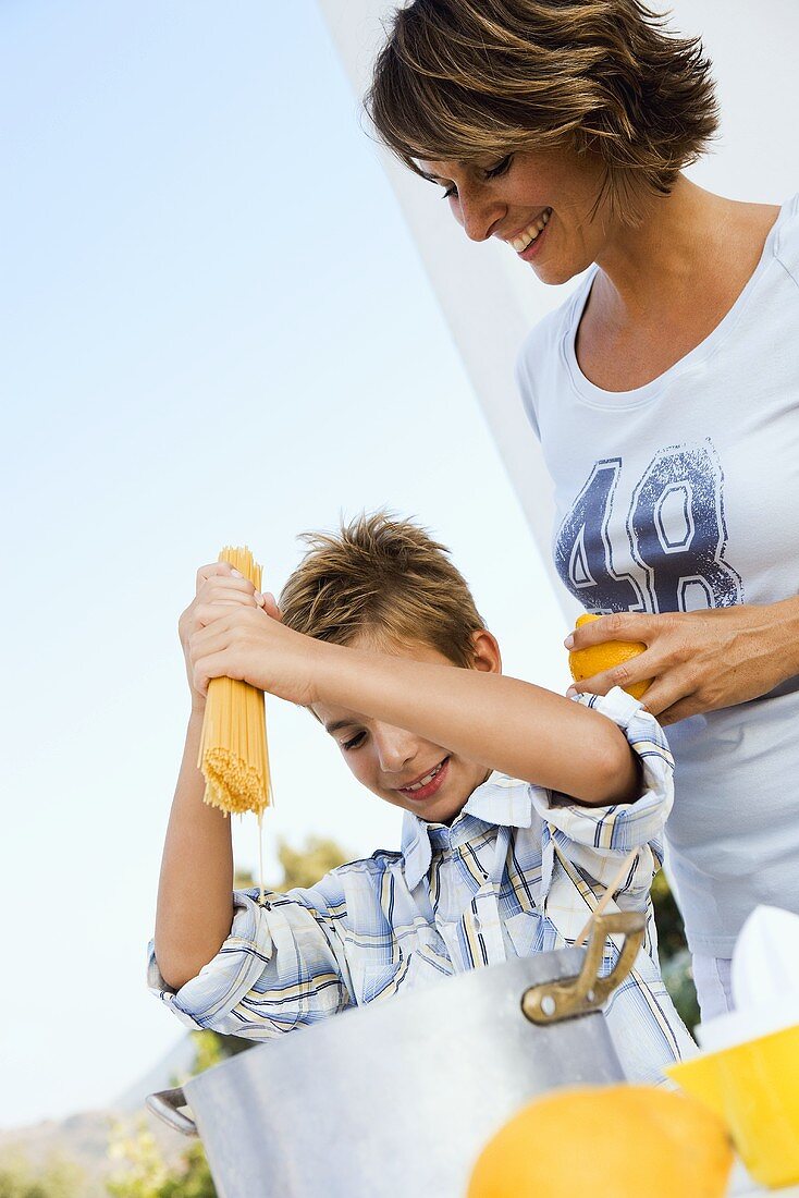 Mother and son cooking spaghetti out of doors