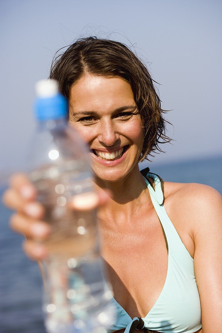 Frau mit einer Flasche Mineralwasser am Strand