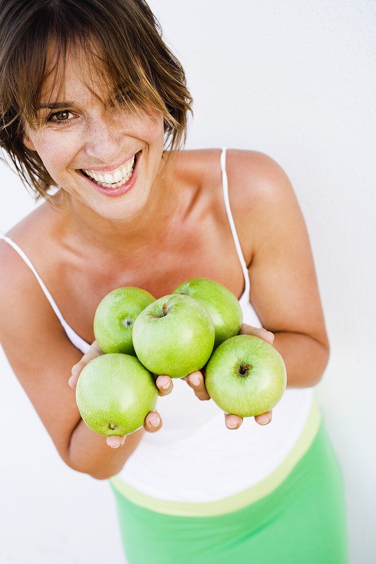 Junge Frau hält grüne Äpfel in den Händen