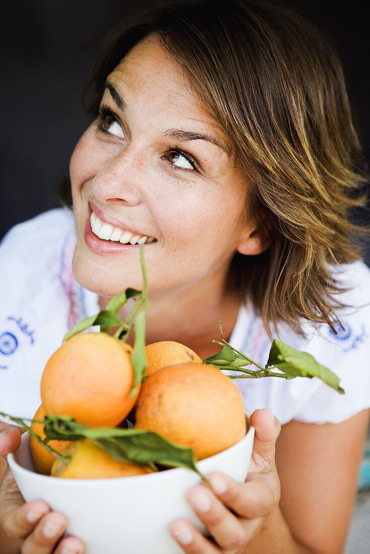 Junge Frau hält eine Schale mit frischen Orangen