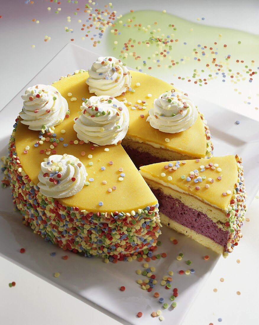 Child's birthday cake with marzipan, sprinkles, whipped cream