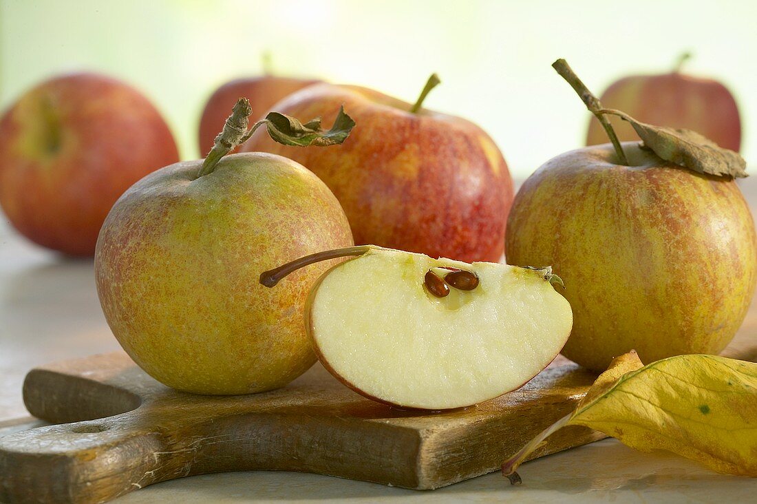 Whole apples and wedge of apple on chopping board
