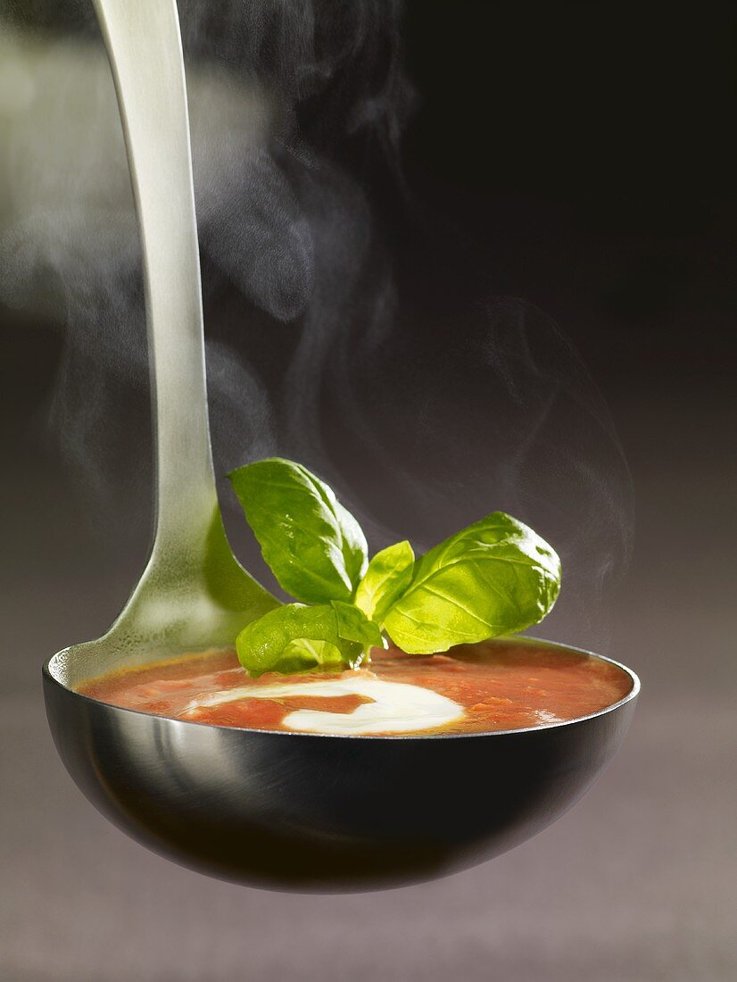 Ladle full of tomato soup with crème fraîche