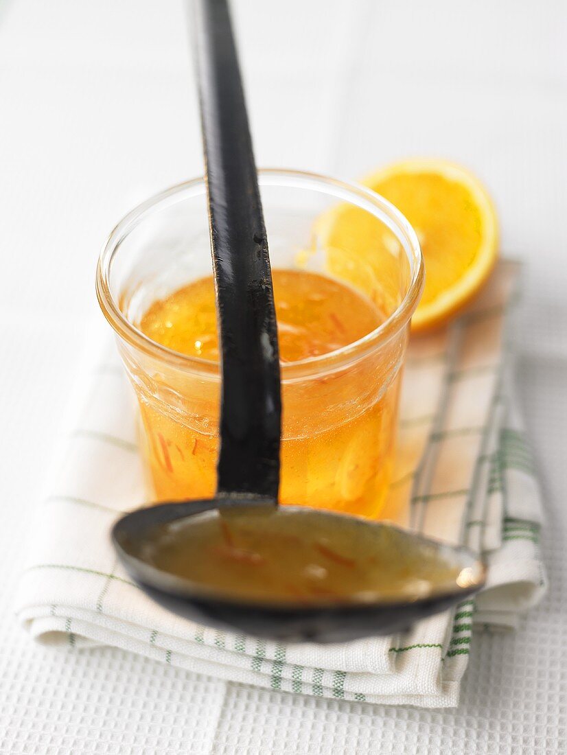Orange marmalade in jar and on ladle