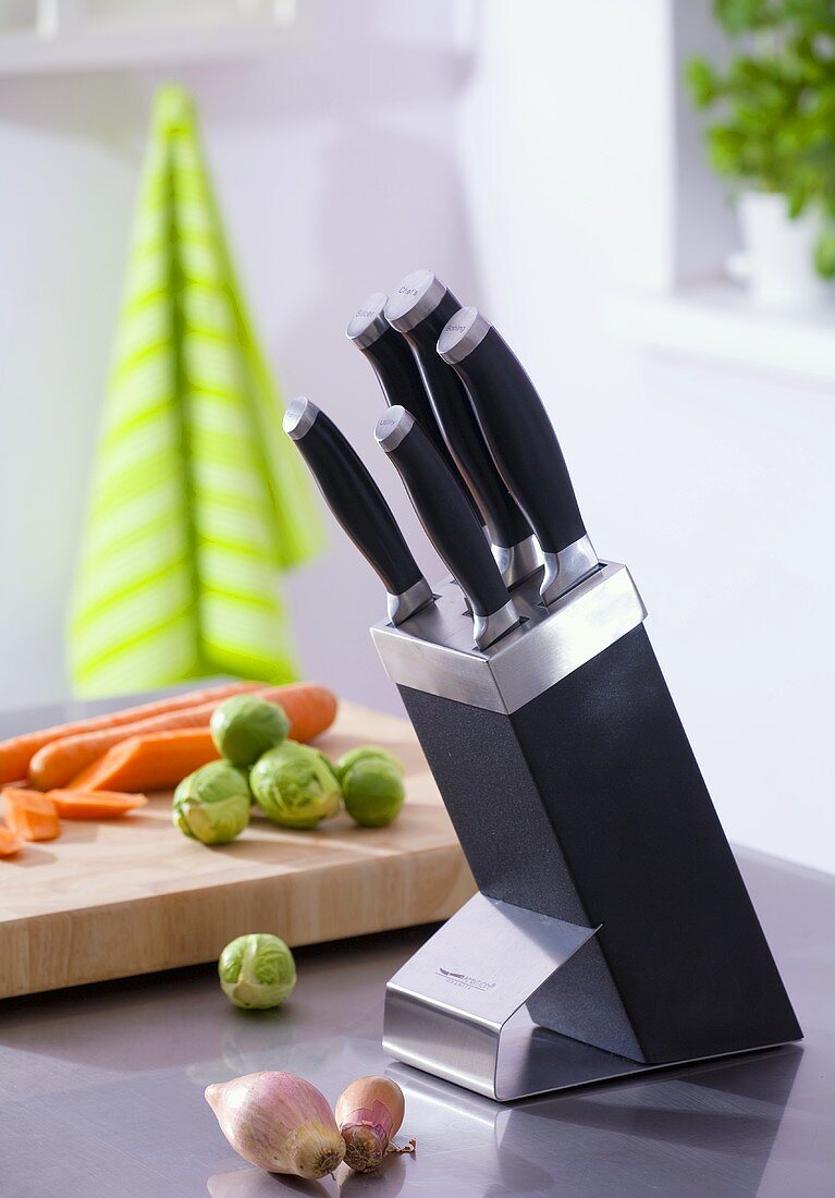 Knife in knife block, vegetables in background