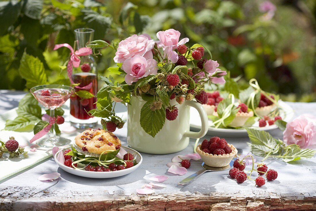 Summery table laid with raspberry dishes out of doors