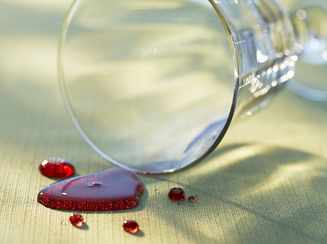 Verschütteter Rotwein vor umgekipptem Glas