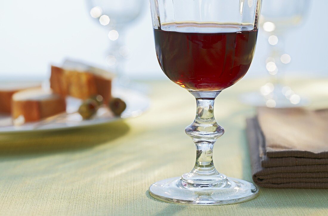 Glass of red wine, napkins, bread and olives on plate
