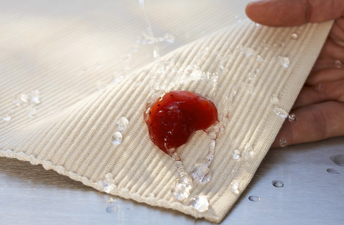 Marmeladenklecks mit Wasser vom Tischset spülen