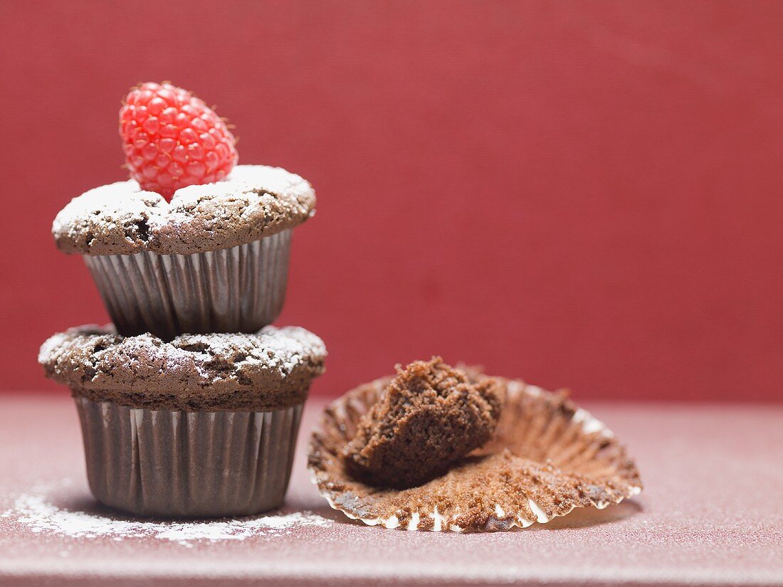 Schokoladenmuffins mit Zucker und Himbeere, eines aufgegessen