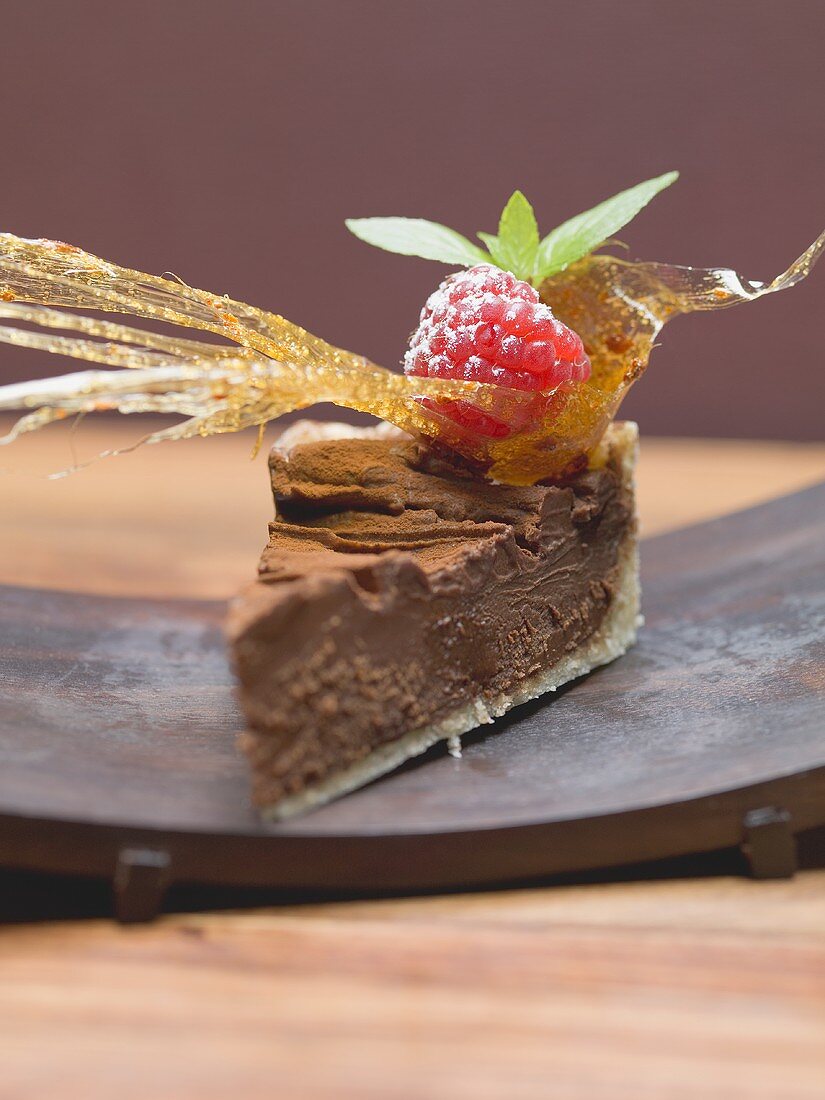 Piece of chocolate torte with a caramel fan and a raspberry