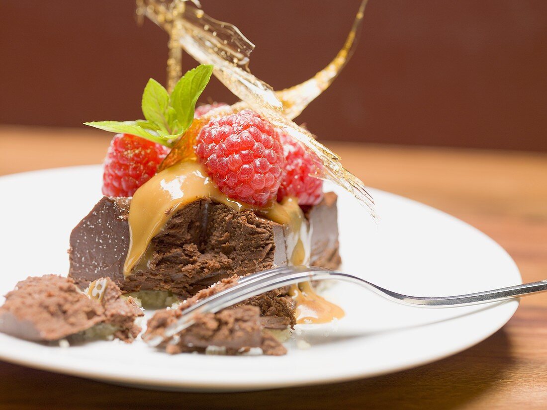 Stück Schokoladentorte mit Himbeeren und Karamell (angebissen)