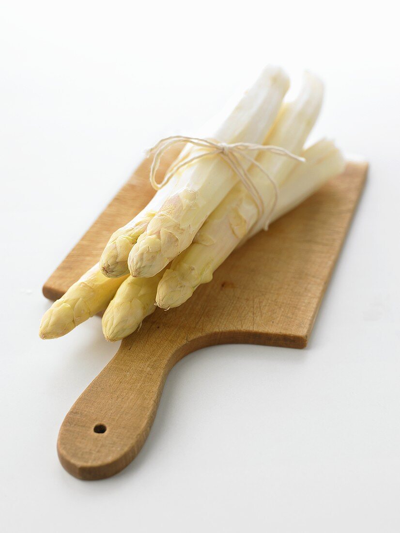 Peeled white asparagus on chopping board