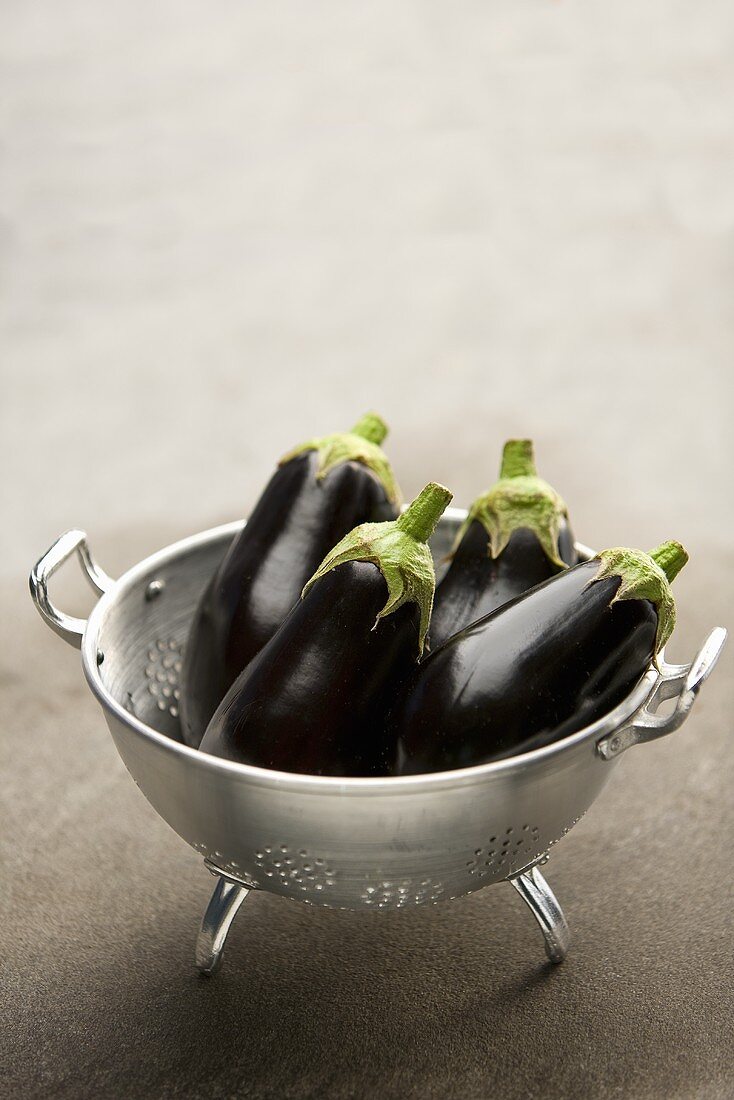 Four aubergines in a colander