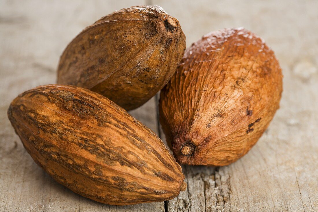 Drei Kakaofrüchte auf Holzuntergrund