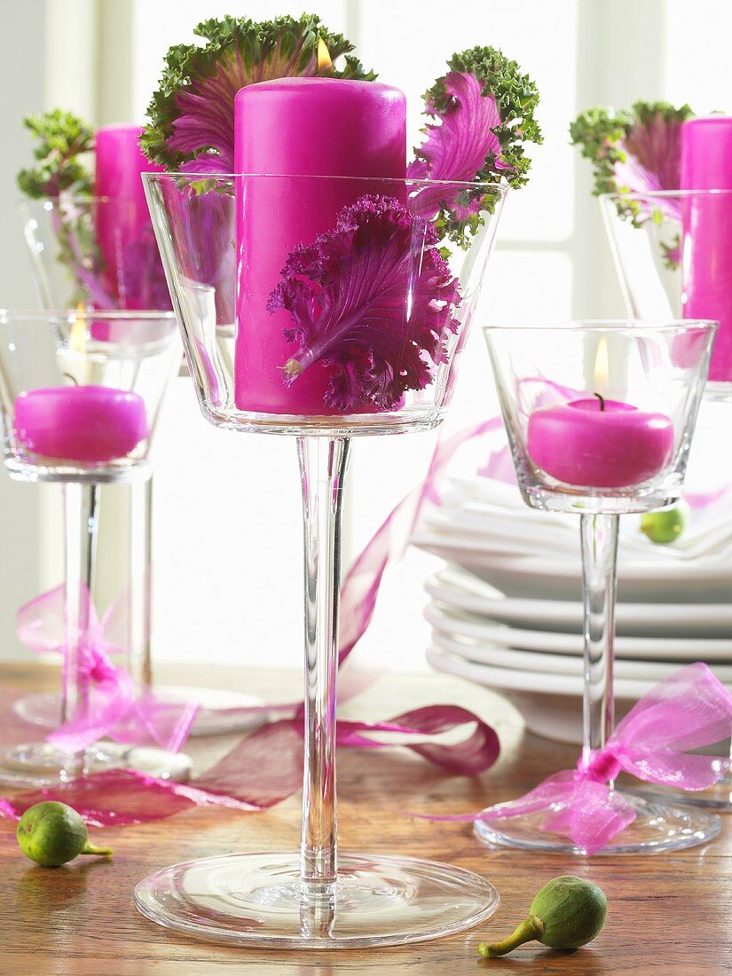 Pink candles and ornamental cabbage leaves in glasses