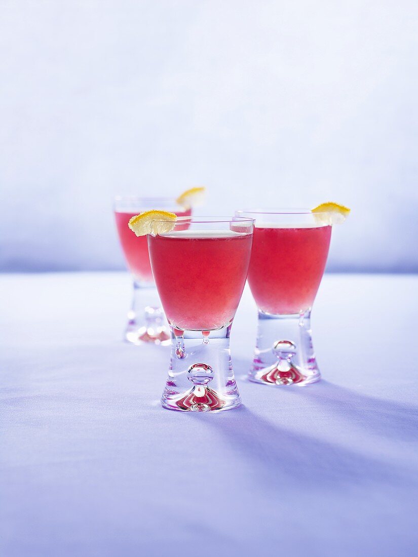 Three pomegranate drinks with pieces of lemon