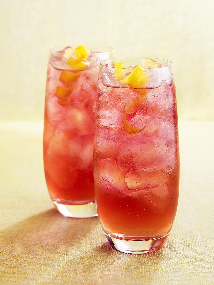 Two drinks made with pomegranate liqueur, with ice & lemon