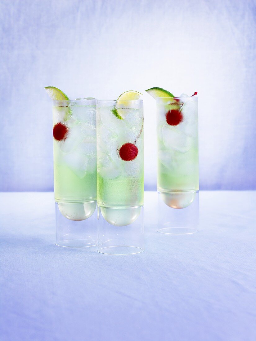 Drei Melonendrinks mit Kirschen, Limetten und Eiswürfeln