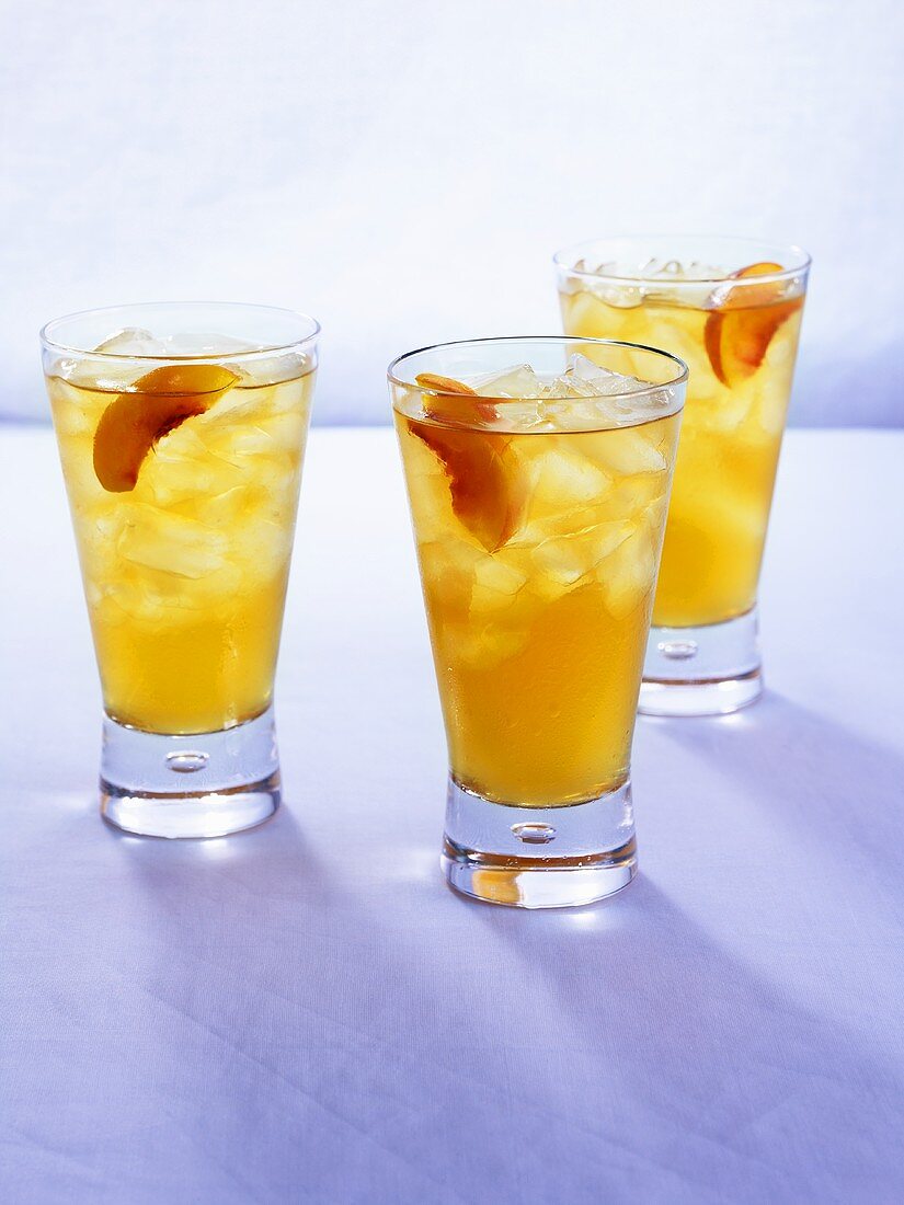 Three peach drinks with ice cubes