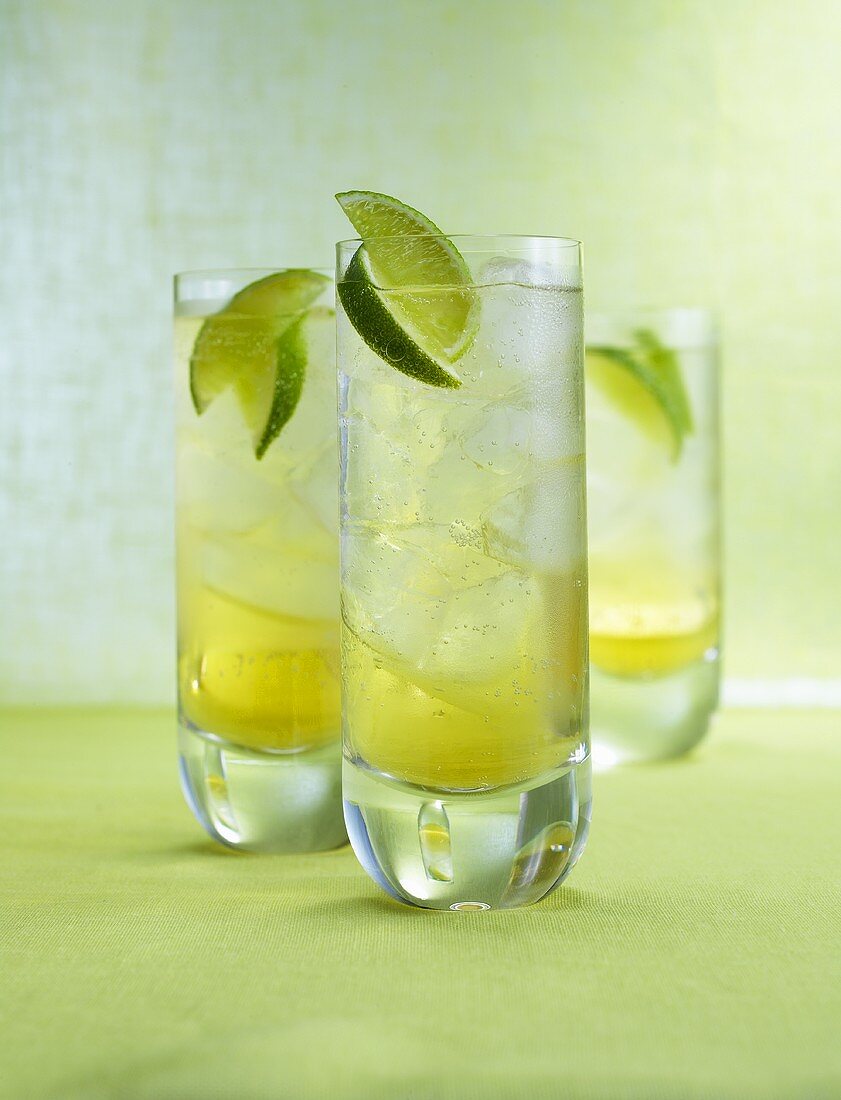 Three Drambuie Sodas with ice cubes and lime wedges