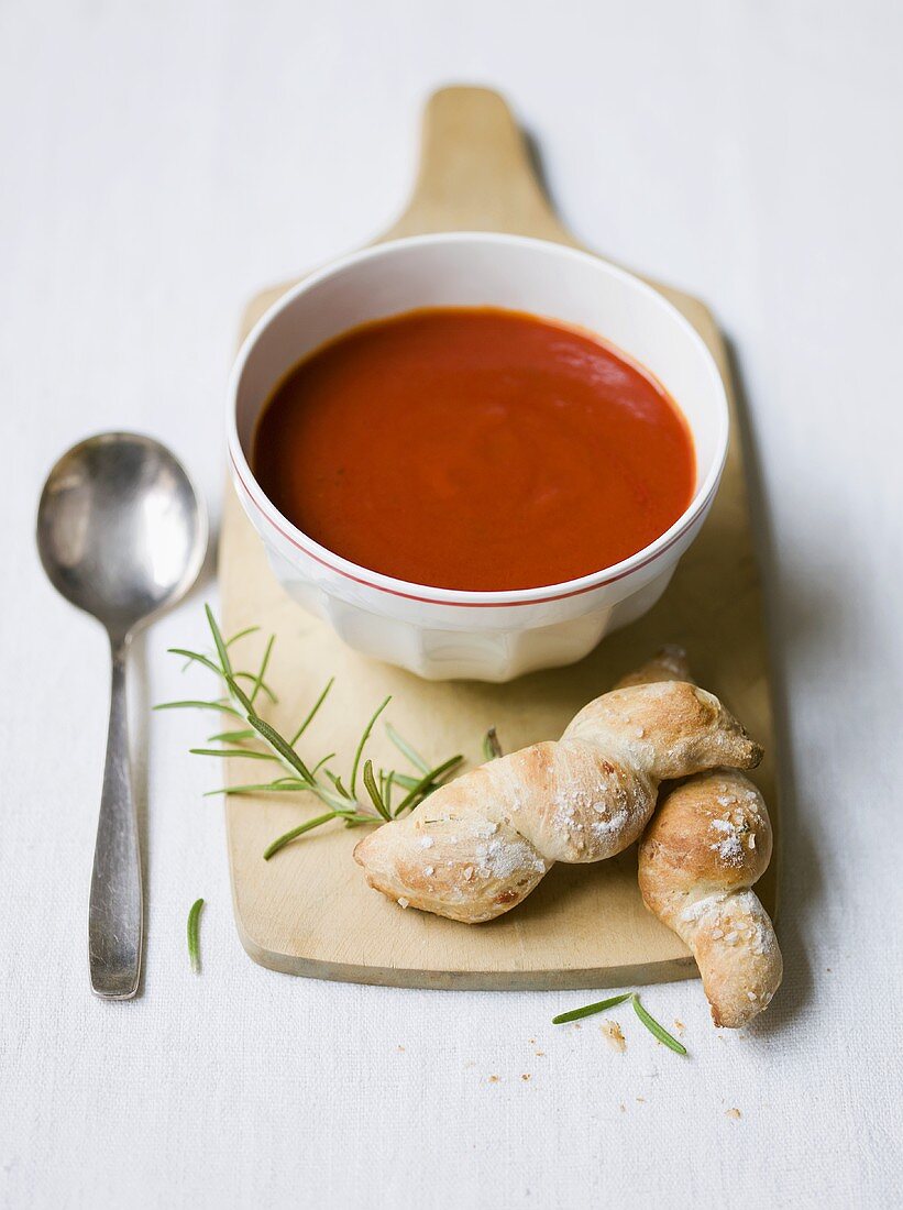 Tomato soup with bread and rosemary on a wooden board