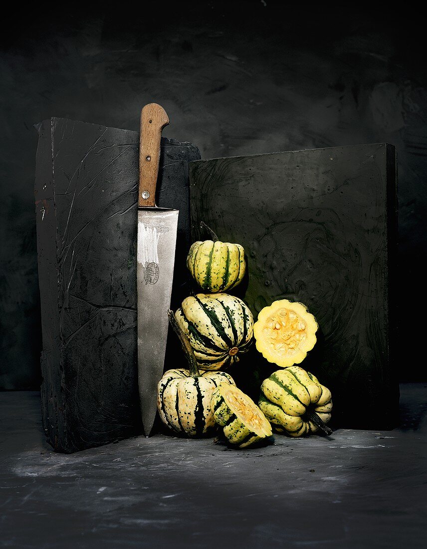 Whole and halved acorn squashes with a knife