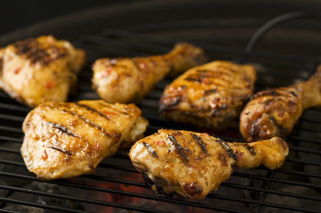 Marinated chicken drumsticks and thighs on a barbecue