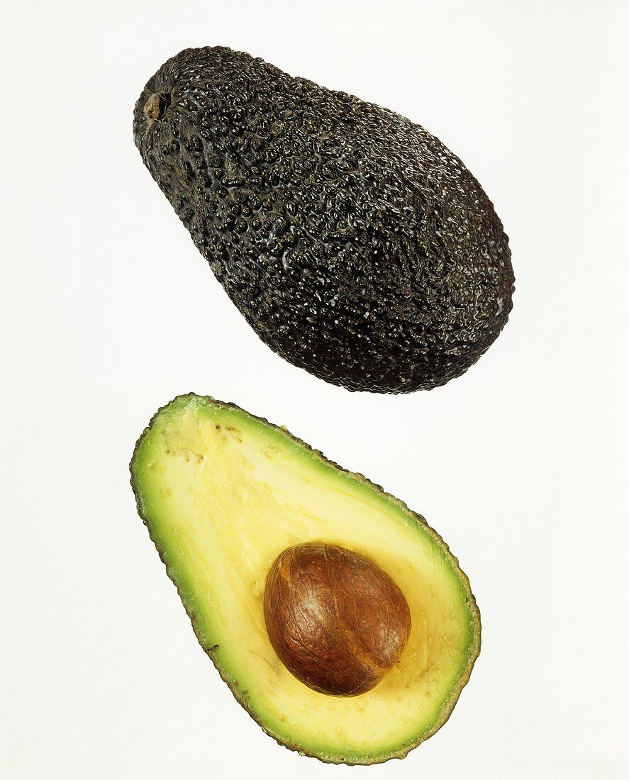 Whole avocado and half an avocado against white background
