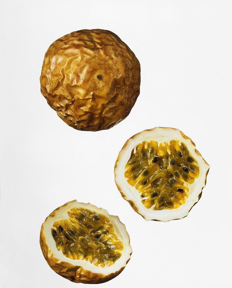Whole and halved passion fruit against white background
