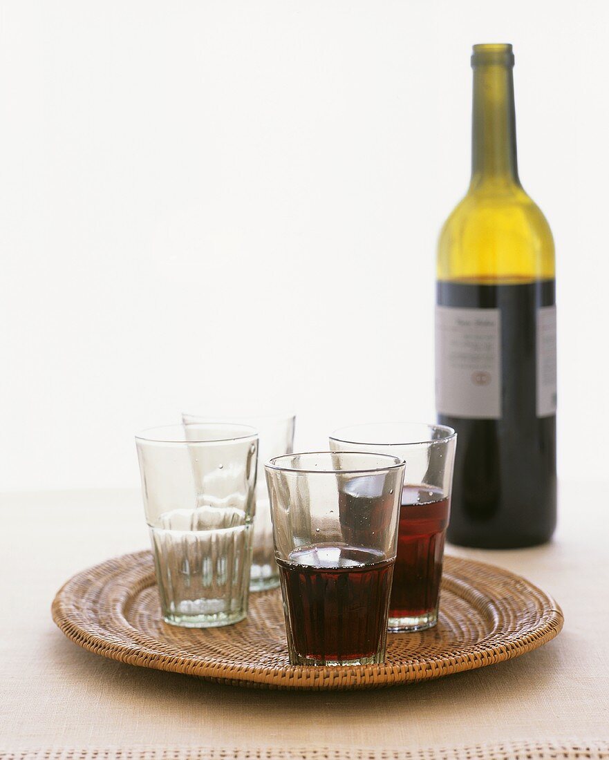 Rotwein in Flasche und Gläser auf Tablett