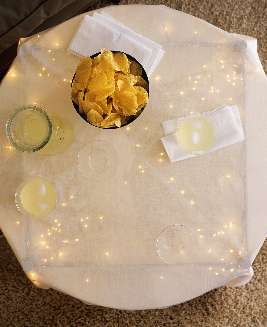 Tisch mit Lichterkette, Chips und Getränken