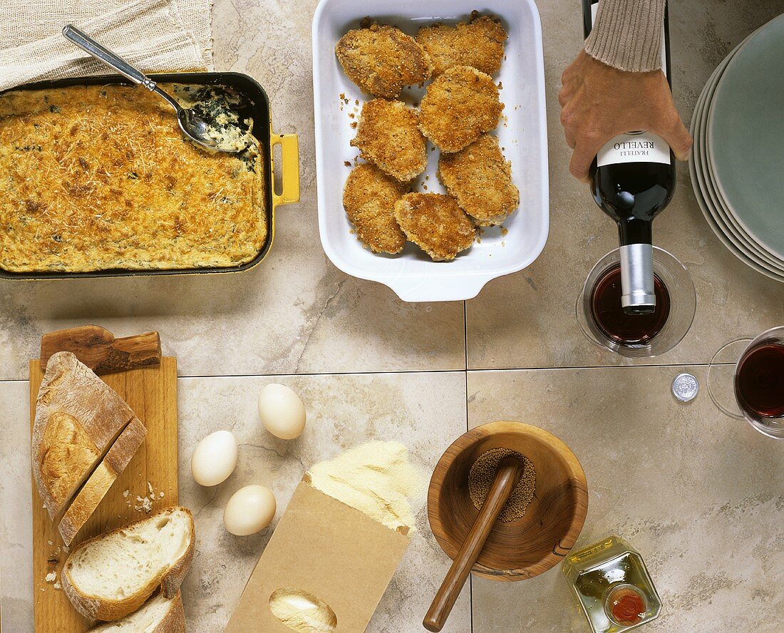Cooked food, bread, ingredients, stack of plates and wine