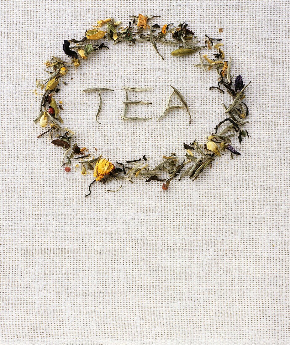 The word TEA in a ring of herbal tea leaves