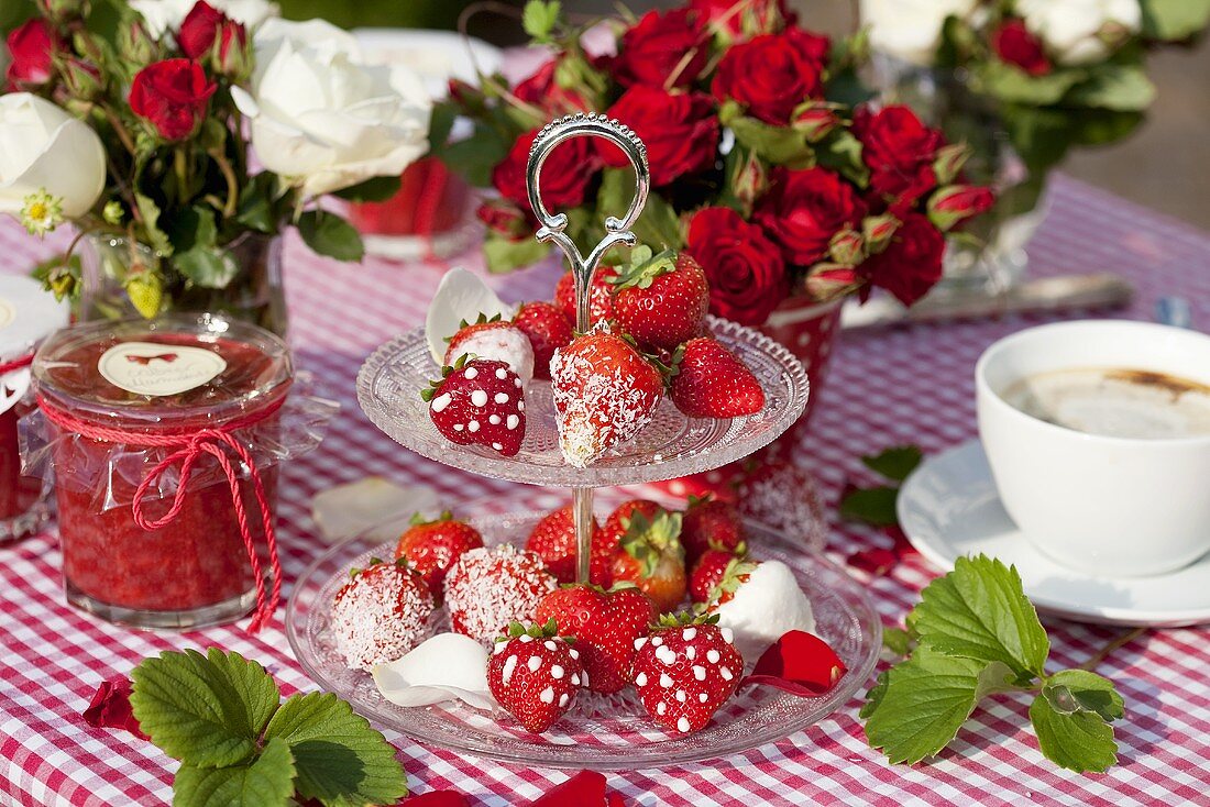 Strawberries with sugar and icing sugar on a cake stand with strawberry jam and coffee