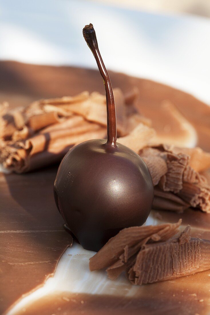 A chocolate-coated cherry and chocolate flakes