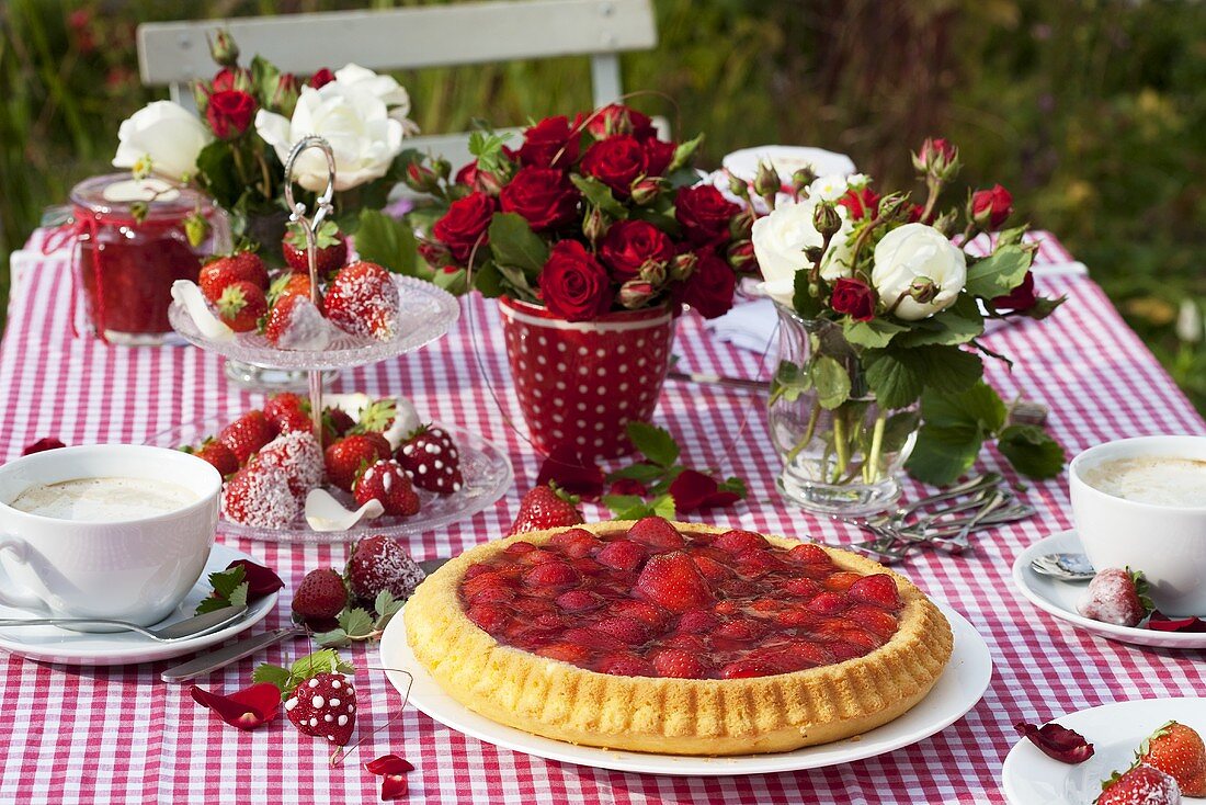 Erdbeertorte, Erdbeeren mit Zuckerguss und Kaffee auf Gartentisch