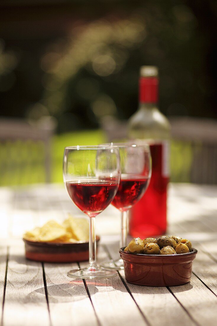 Rosé wine, olives and crisps on a garden table
