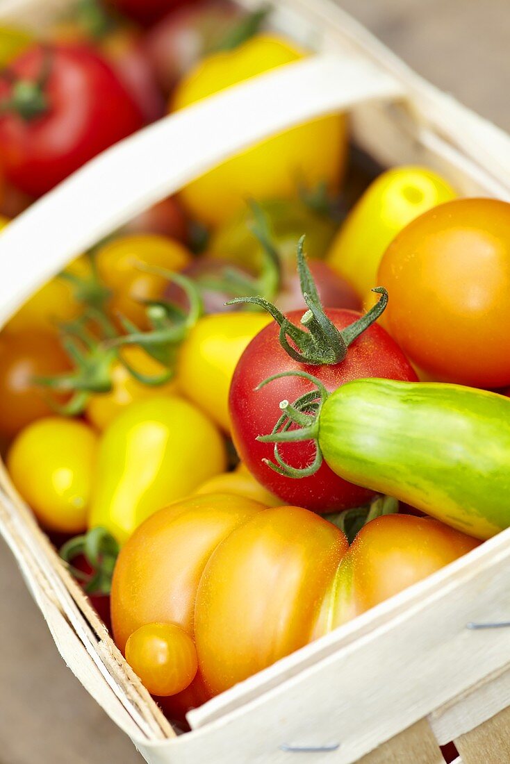 Various types of tomatoes in a wooden basket (close up)